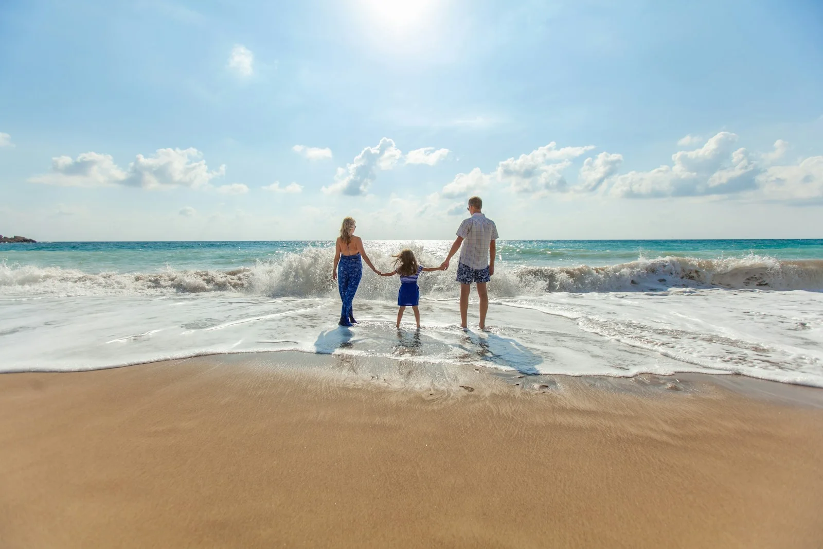 Família de mãos dadas na praia ao entardecer